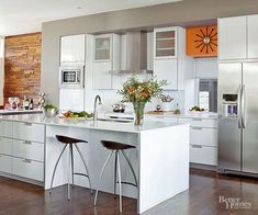 a modern kitchen with white cabinets and stainless steel appliances, including two bar stools