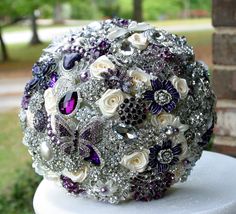 a bridal bouquet sitting on top of a white pedestal in front of some bushes