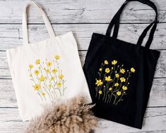 two totes bags with yellow flowers on them sitting next to a fur ball and some wood planks