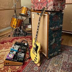 a yellow guitar sitting on top of a wooden floor next to a amplifier and other musical equipment