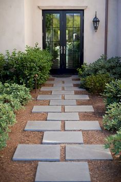 an entry way to a home with stone walkways and plants in front of it