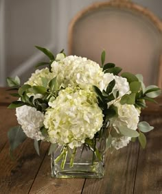 a vase filled with white flowers on top of a wooden table