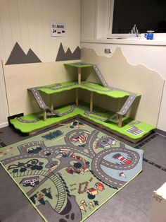 a child's play area with green shelves and toys on the floor in front of it