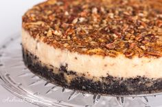 a cheesecake on a glass plate with nuts in the crust and crumbs all over it