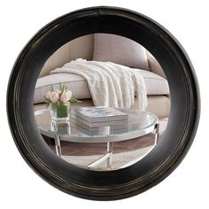 a round mirror reflecting a couch and table