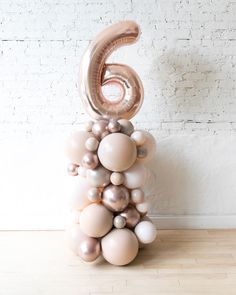 the number six balloon sculpture is made out of balloons and metallic foil, on top of a wooden floor