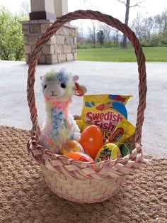 a stuffed lamb sitting in a basket filled with candy and candies on the ground