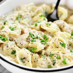 a white bowl filled with pasta covered in parsley