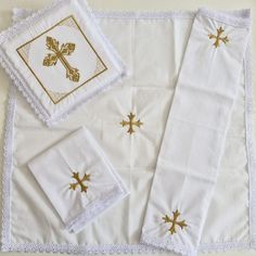 white linens with gold crosses on them are laid next to each other and folded napkins