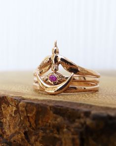 a stack of gold rings with an amethorate stone in the middle on top of a piece of wood