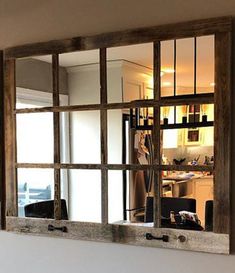 a mirror that is on the wall in front of a kitchen door with an open window