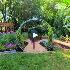 a woman is standing in the middle of a garden with flowers and plants around her