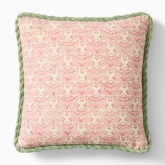 a pink and green pillow sitting on top of a white wall