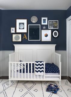 a baby's room with blue walls and white crib in the corner, framed pictures on the wall