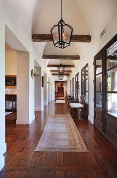 a long hallway with wood floors and chandelier hanging from it's ceiling