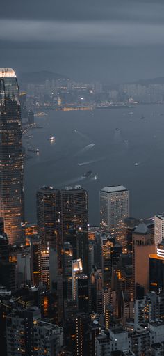 an aerial view of the city lights and water in the background at night, with skyscrapers lit up