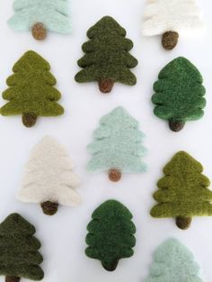 felt christmas trees are arranged on a white surface