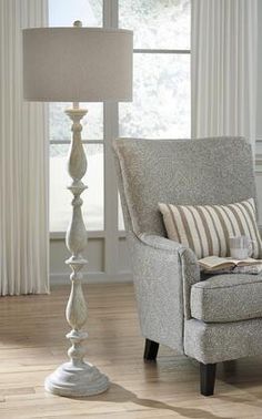 a living room with a chair, lamp and window in it's centerpiece