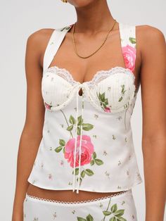 Adorned with a sweet allover floral print, the Rosebud white corset top exudes all things feminine. Crafted in a sleek satin, this camisole top is detailed with lace trimmed cups, and halter straps that cross and tie at the back.