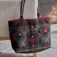 a red and green plaid purse sitting on top of a couch next to a chair