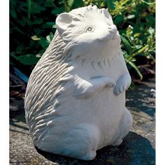 a white bear statue sitting on top of a rock in front of some bushes and plants