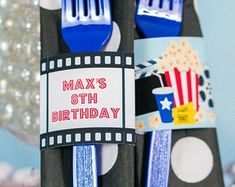 two forks decorated with movie themed labels and some decorations in the shape of popcorn boxes