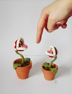 a hand reaching for two small pots with plants in them