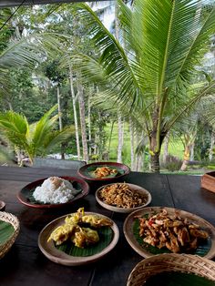 several plates of food on a table with palm trees in the background