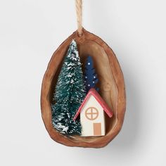 a small house is in a hanging ornament with christmas trees on the top