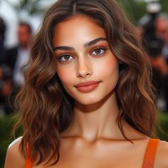 an image of a woman with brown hair and blue eyes posing for the camera in front of photographers