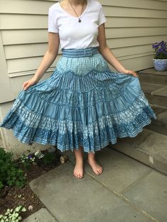 "This beautiful Suttles and Seawinds western style full skirt is designed with layered ruffles. The six layered ruffles are made from different, but complementary blue print fabrics with bias tape detail between each layer.  Gorgeous fabric and craftsmanship! The skirt length is 32\". There is an waist 28\" with an accompanying 2\" wide belt. And two side inset pockets. One of a kind!  Designed by Vicki Lynn Bardon Suttles and Seawinds- Nova Scotia. (If you are not familiar with this unique designer and shop you can look it up) Perfect to wear to any summer event or square dance!" Blue Tiered Bottoms With Ruffle Hem, Tiered Cotton Skirt With Ruffles, Bohemian Bottoms With Tiered Layered Hem, Bohemian Tiered Bottoms With Layered Hem, Tiered Blue Skirt With Ruffles, Blue Lined Tiered Skirt, Bohemian Dress With Ruffled Full Skirt, Blue Tiered Lined Skirt, Bohemian Blue Tiered Bottoms