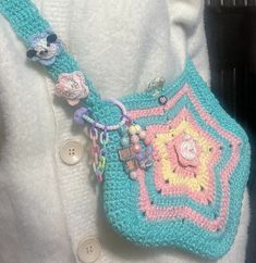 a crocheted purse is being held by someone's hand while wearing a white shirt