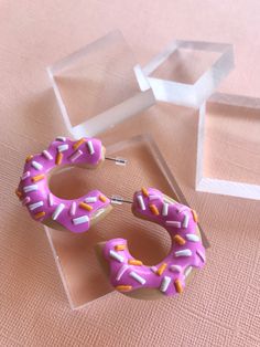 These handmade polymer clay hoop earrings feature donuts with a bite taken out. They are kawaii food inspired, and make a cute, smaller statement for any outfit. | Donut Hoop Earrings, Half Eaten Donut Earrings, Cute Earrings, Kawaii Earrings, Baked Goods Earrings, Donut Jewelry, Statement Earrings Polymer Clay Hoop Earrings, Clay Hoop Earrings, Donut Jewelry, Donut Earrings, Homemade Clay, Earrings Kawaii, Food Inspired, 3d Jewelry, Unique Handmade Earrings