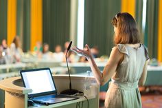 a woman standing in front of a podium with a laptop on it's lap