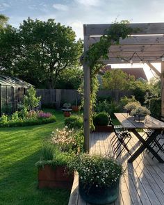 a wooden deck surrounded by plants and flowers