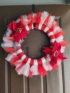 a red and white tulle wreath with poinsettis on the front door