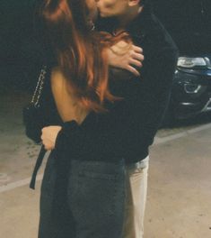 a man and woman kissing in front of a car