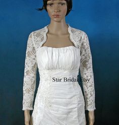 a mannequin wearing a white dress and jacket with lace on the sleeves,