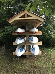 several surfboards are stacked on top of each other in front of some trees and bushes