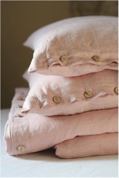 three pillows stacked on top of each other with buttons in the middle one is pink