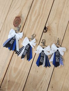 three ribbons are attached to key chains on a wooden table