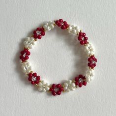 a red and white beaded bracelet on a white surface