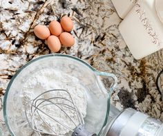 eggs and flour in a blender on a marble counter top next to other ingredients