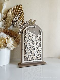 a white vase filled with flowers on top of a table next to a wooden sign