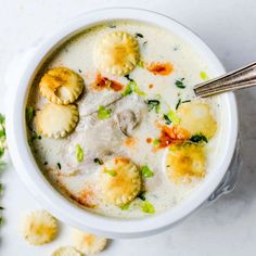 a white bowl filled with soup and dumplings on top of a table next to broccoli