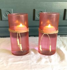 two red glass vases with candles in them