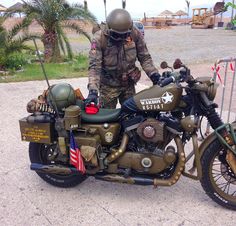 a man standing next to an army motorcycle