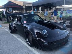 a black sports car parked in front of a building with people looking at it from the side