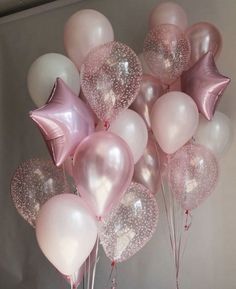 a bunch of pink and white balloons with stars on them are in a vase next to a wall