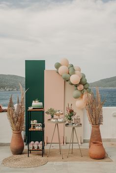 an outdoor party setup with balloons and palm trees on the side of the road next to the ocean